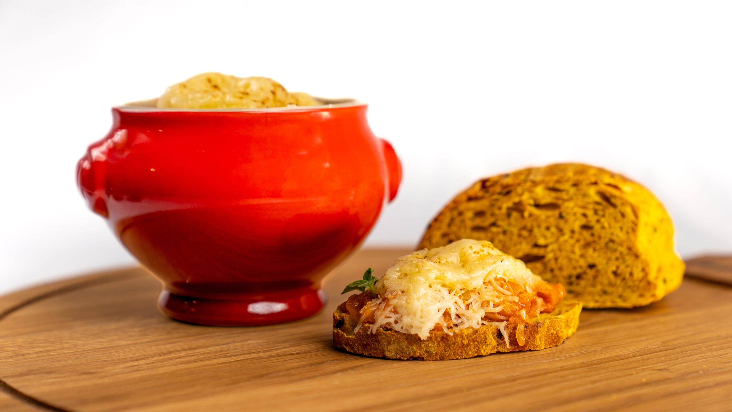 Zuppa di cipolle veg gratinata, servita su bruschetta di pane caldo strofinato all’aglio