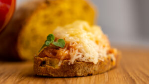 Porzione di zuppa di cipolle vegan con strati di pane tostato visibili e crosta dorata leggera