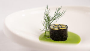 Mosaico di cipollotti e alga nori, ricetta vegana salata con umami naturale, servito su crema di piselli frullata e setacciata, piatto sostenibile, leggero e zero sprechi.