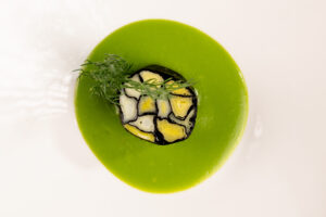 Mosaico di cipollotti e alga nori, ricetta vegana salata con sapidità naturale e umami, servita su crema di piselli liscia e setacciata, piatto sostenibile e zero sprechi.