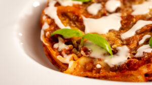 Lasagna di lenticche plant-based con lenticchie, strati di ragù e besciamella, decorata con timo e e foglia di basilico