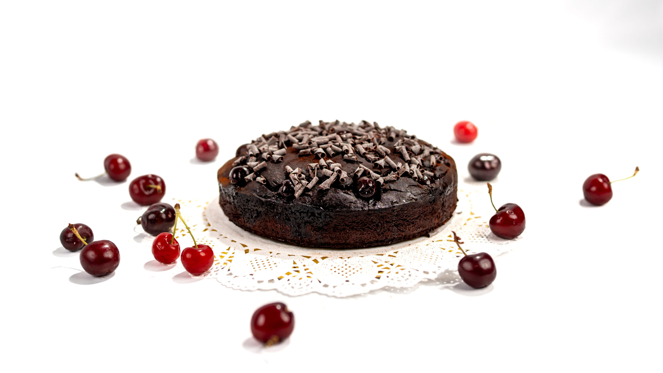 Torta al cacao vegana con amarene o ciliegie senza burro e senza uova, decorata con riccioli di cioccolato e cacao amaro