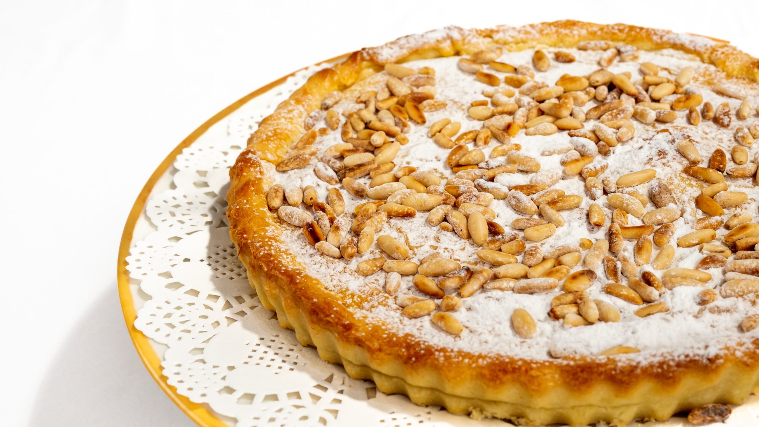 orta della nonna vegana senza burro e senza uova, torta intera dorata con crema al limone e pinoli